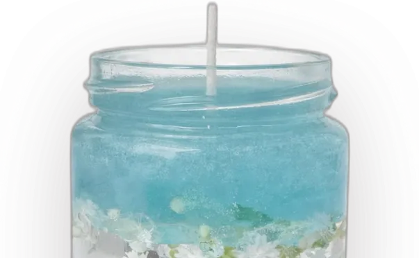 A gel candle in a glass jar: sea-blue gel over a clear layer with white flowers and shells, on white sand